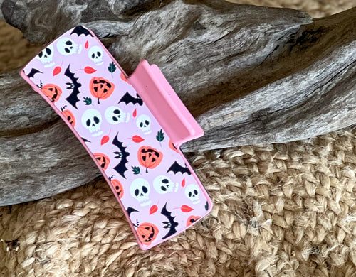 Pink Halloween Hair Claw with friendly bats, pumpkins, and skulls on a pastel pink background – handmade in the Outer Banks