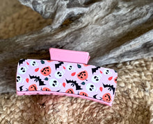 Pink Halloween Hair Claw with friendly bats, pumpkins, and skulls on a pastel pink background – handmade in the Outer Banks